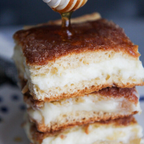 three sopapilla cheesecake bars with drizzled honey on top.