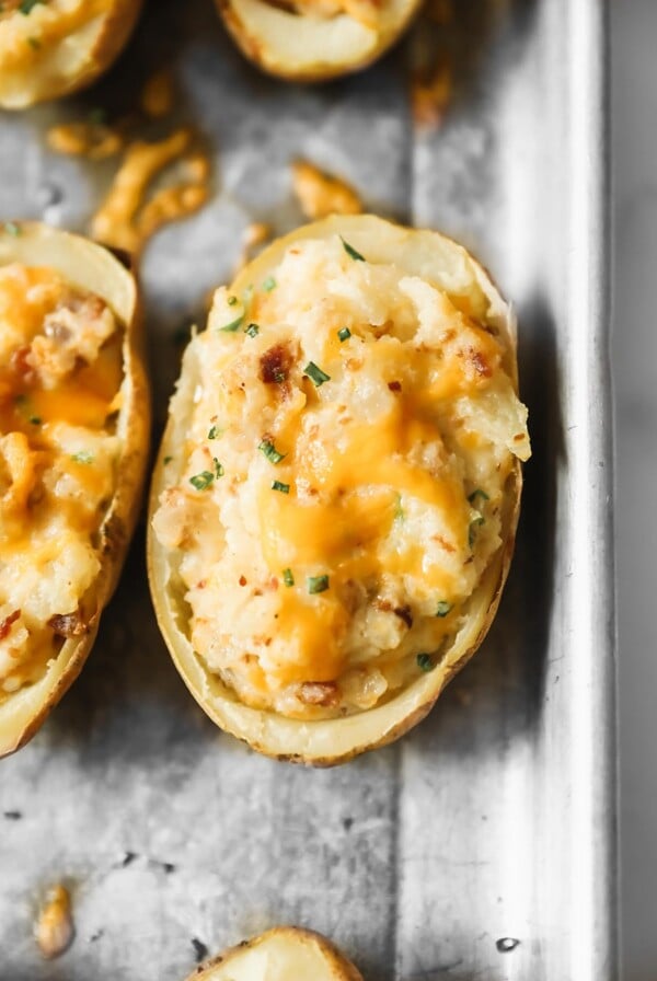 twice baked potato with melted yellow cheese and green herbs on top.