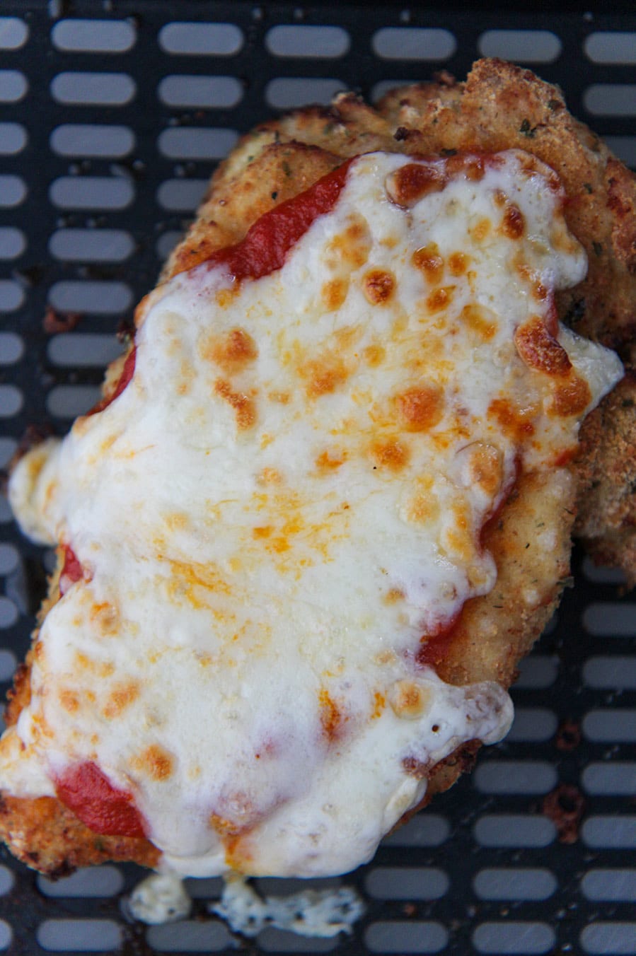 chicken parmesan in the black air fryer basket.