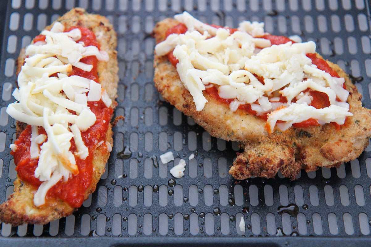 two chicken breasts with sauce and shredded cheese on top. 