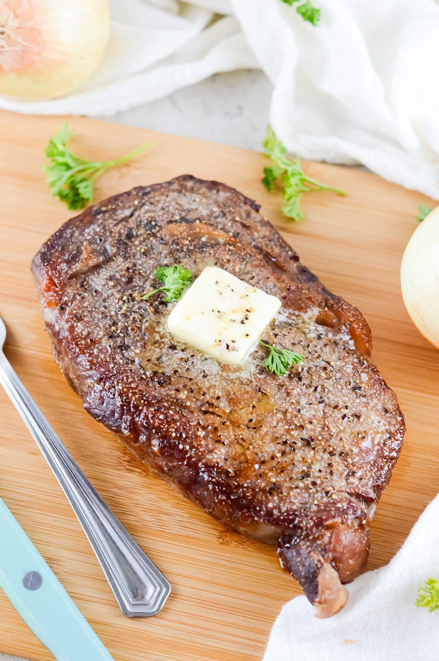 air fryer cooked steak with butter and parsley on top.