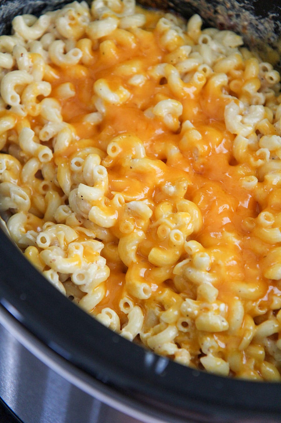 mac and cheese in the crockpot with yellow melted cheese on top