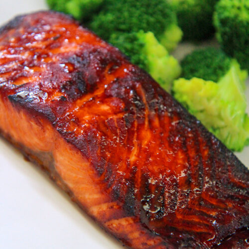 cooked air fryer salmon on a white plate with broccoli