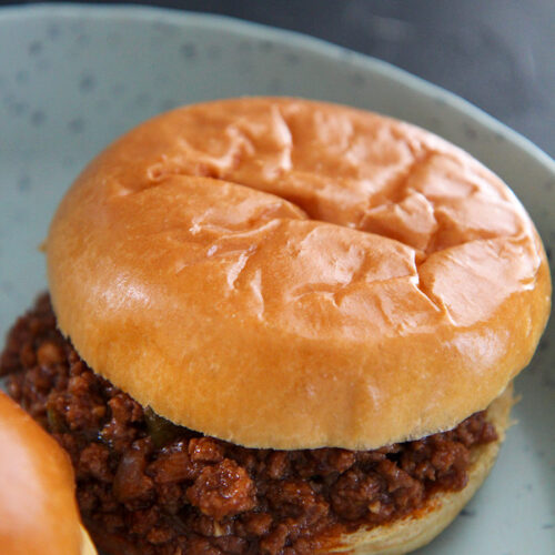 a sloppy joe up close on a blue plate.