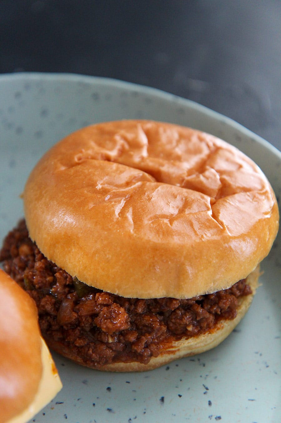 a sloppy joe up close on a blue plate.