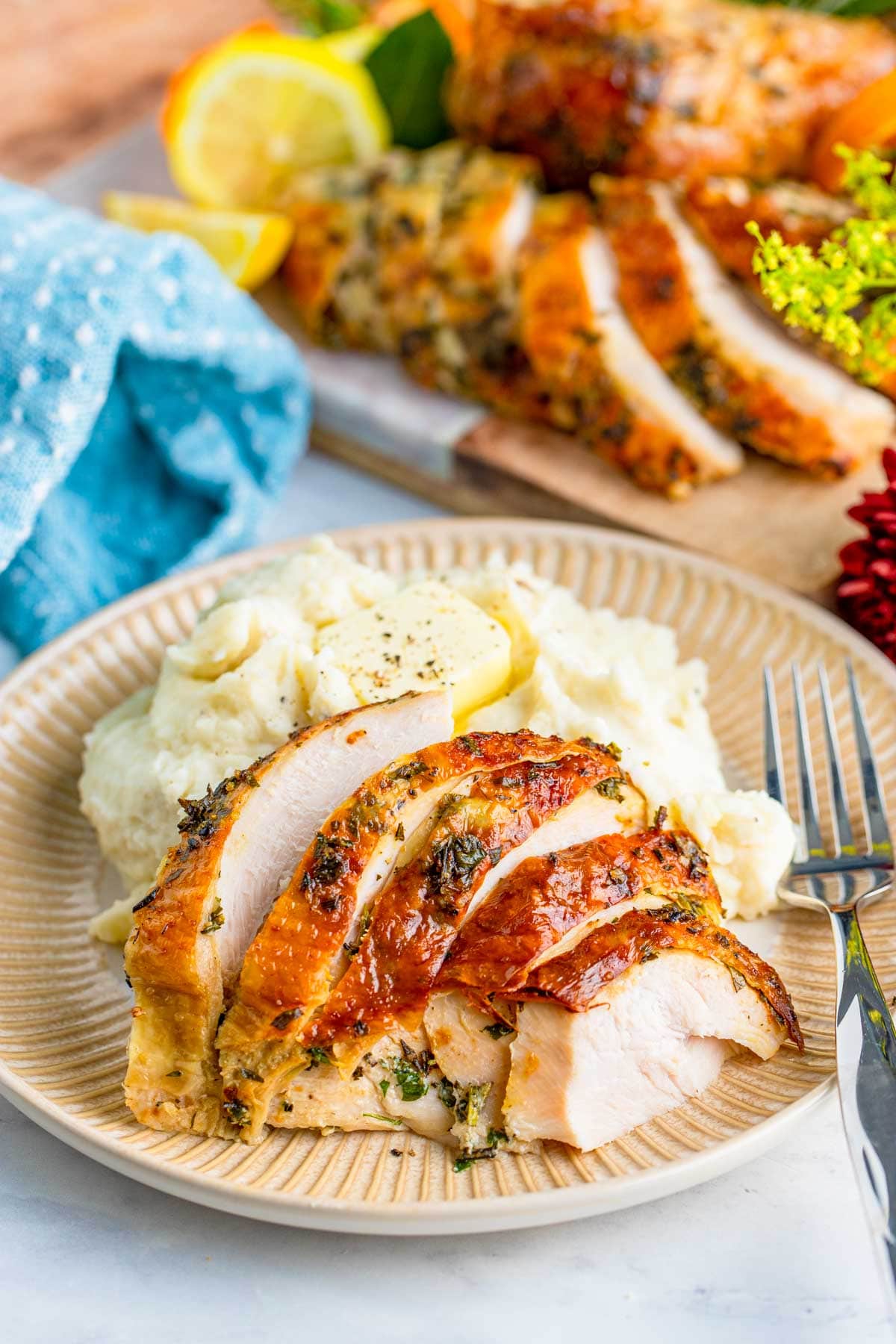 sliced juicy roast turkey breast with mashed potatoes and a fork on a plate. 