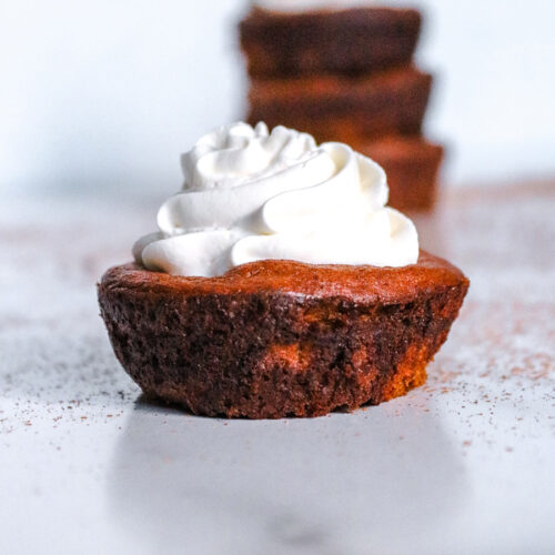 keto mini pumpkin pie up close with whipped cream on top.