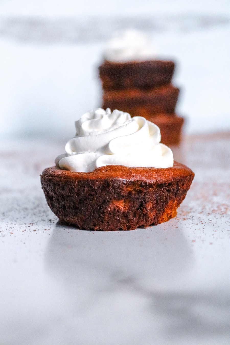 keto mini pumpkin pie up close with whipped cream on top.