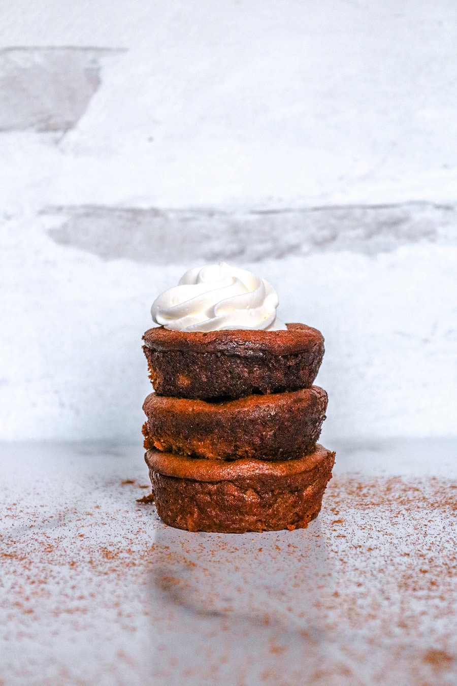 three mini pumpkin pies stacked on top of each other with whipped cream. 