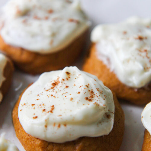 pumpkin cookies with cream cheese frosting and cinnamon on top.