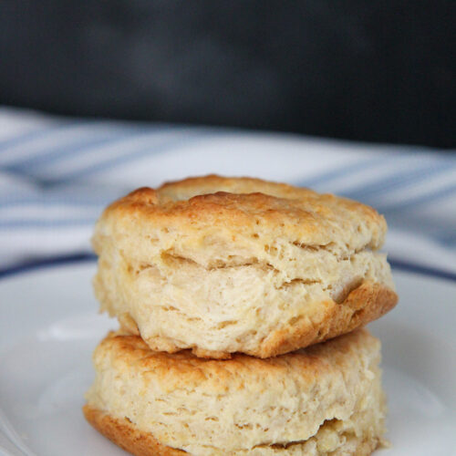 two buttermilk biscuits stacked on top of each other on a white and blue plate.