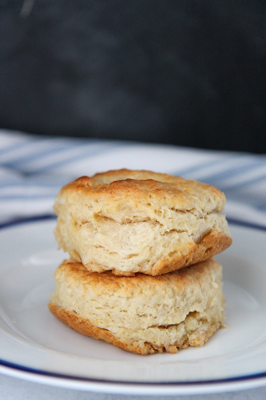 two buttermilk biscuits stacked on top of each other on a white and blue plate.