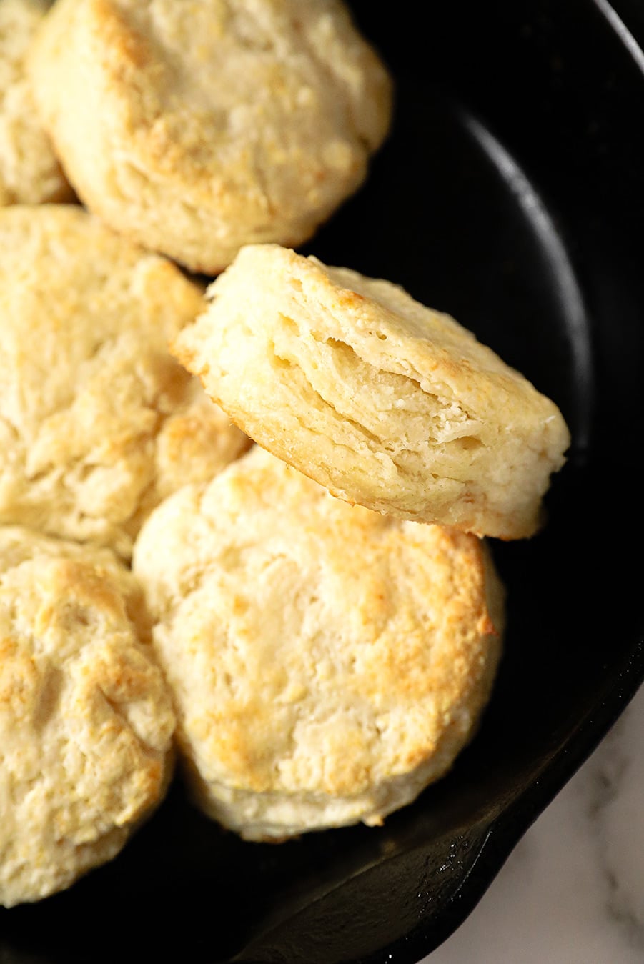 baked biscuits in a cast iron skillet and one biscuit up close.