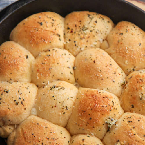 baked cheese stuffed rolls in a cast iron skillet with a blue and white towel on the side.