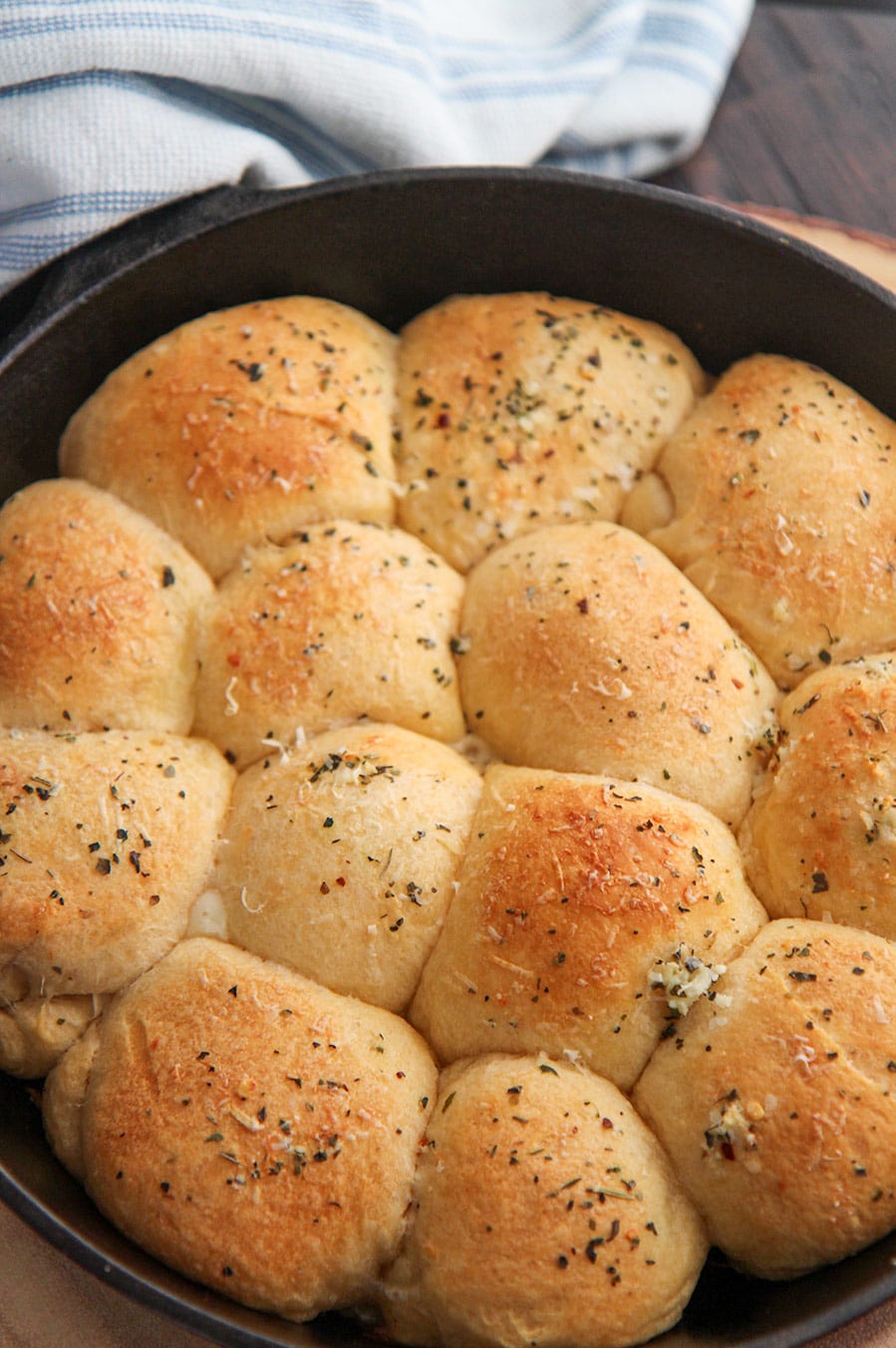 baked cheese stuffed rolls in a cast iron skillet with a blue and white towel on the side.