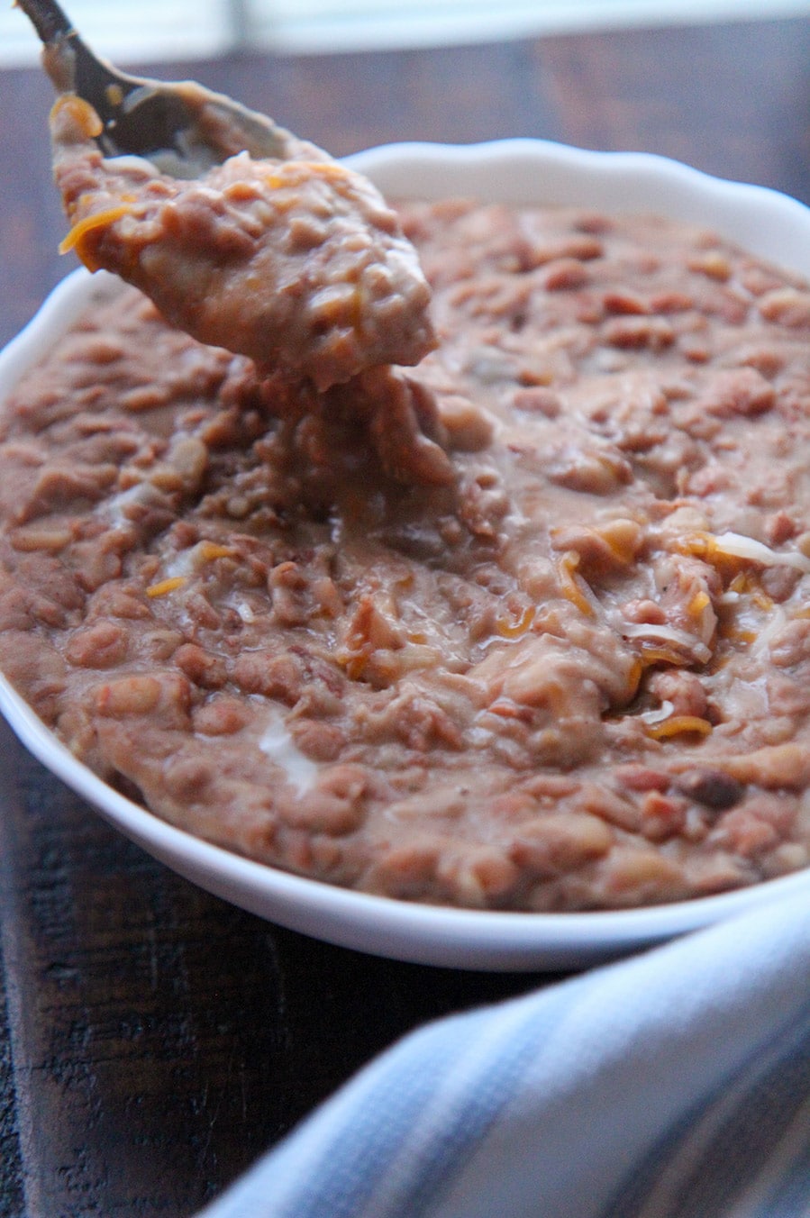 chunky pinto beans with melted cheese and a spoon.