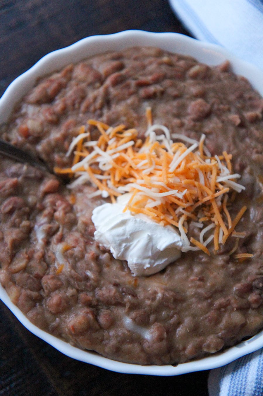 beans in a white bowl with sour cream and cheese on top. 