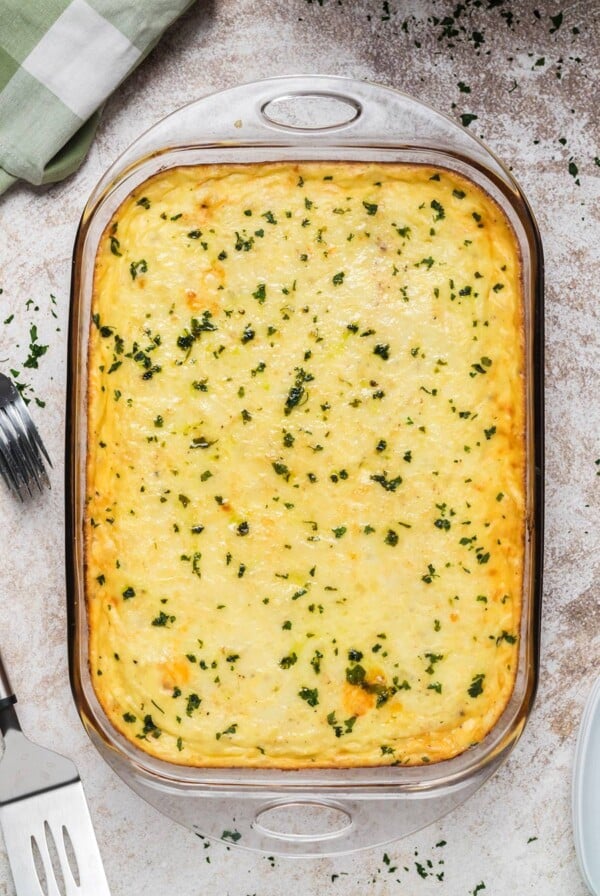 Baked pastitsio in a glass baking dish with chopped parsley on top.