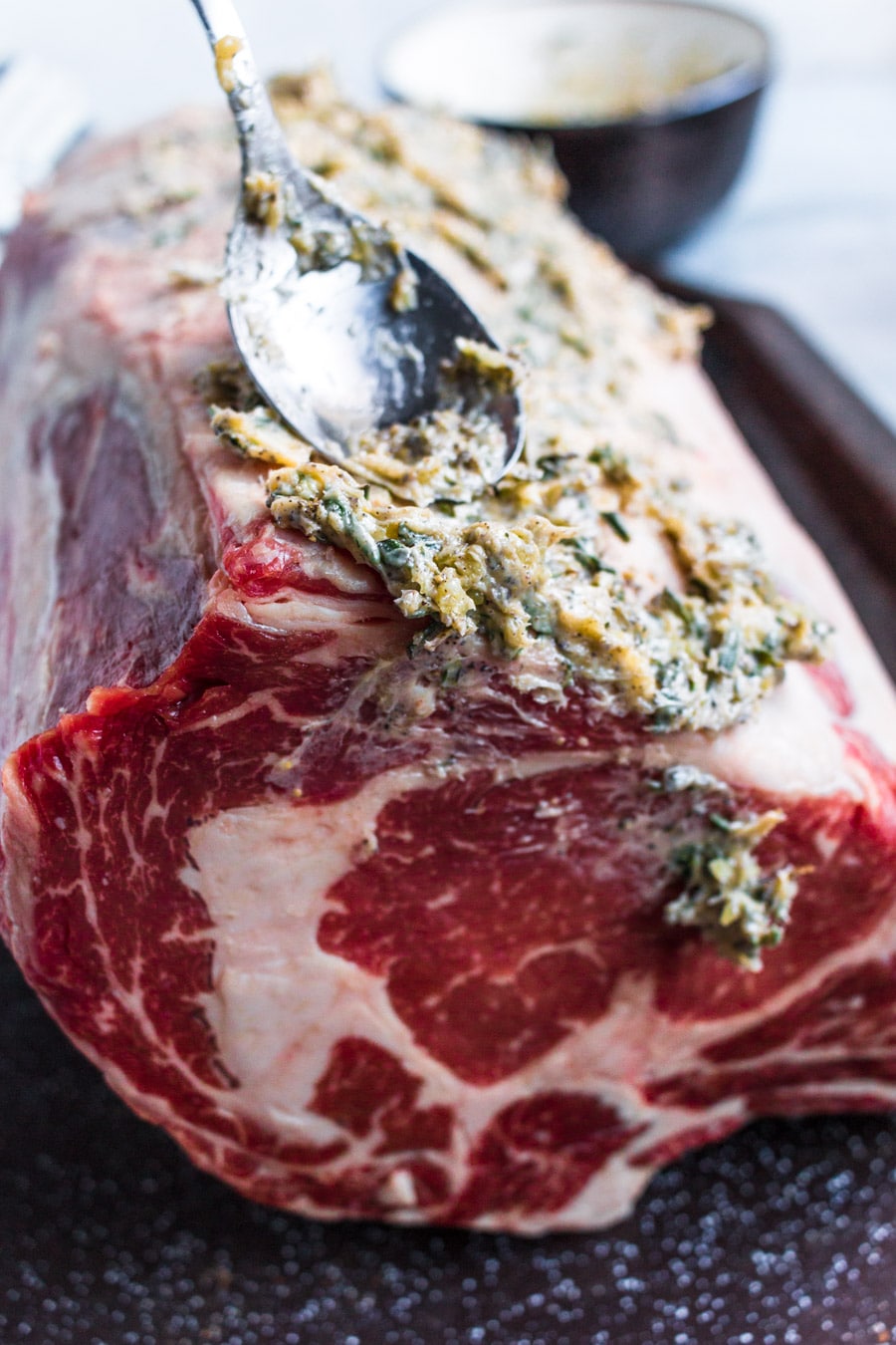 raw prime rib with herb butter and a spoon. 