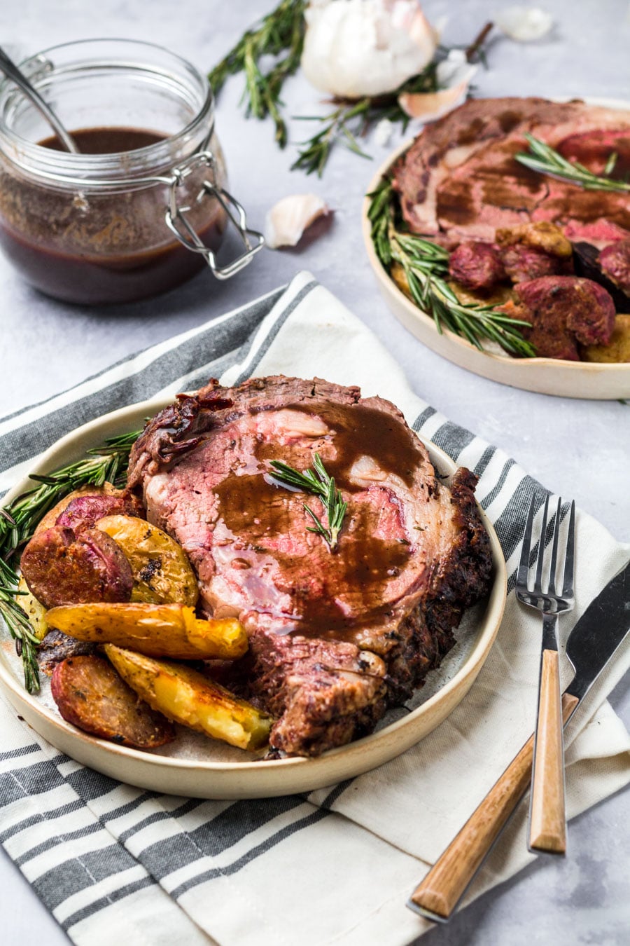 prime rib with au jus served with potatoes on a plate.