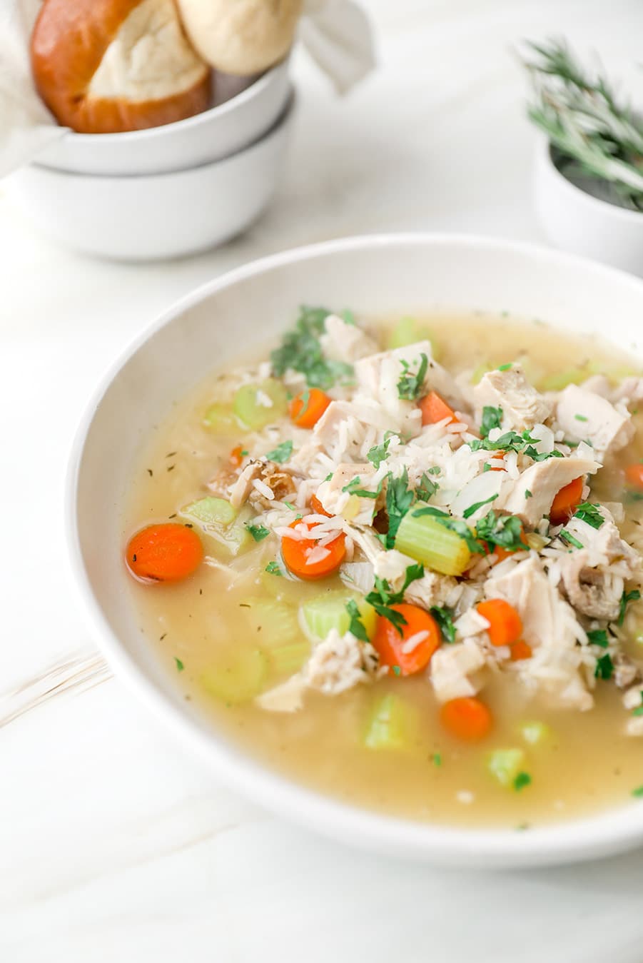 soup in a white bowl up close and a small bowl filled with bread in the background. 