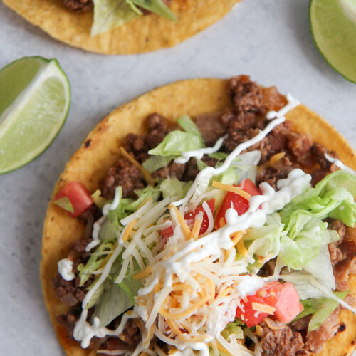 beef tostadas up close with two lime wedges.