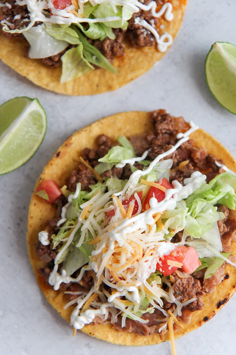 beef tostadas up close with two lime wedges.