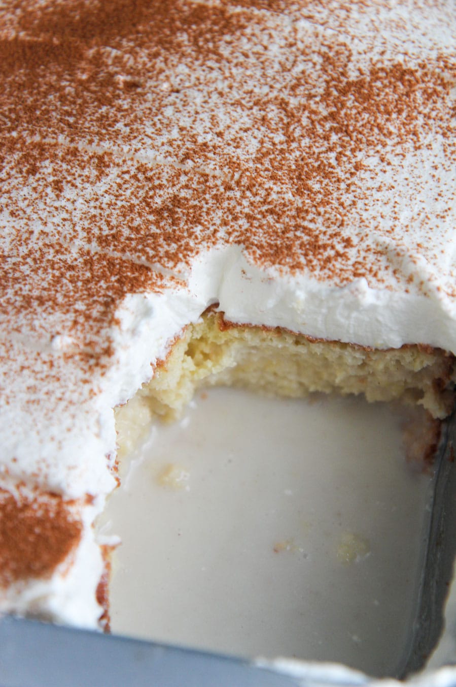 a coquito cake with a missing slice in a baking dish. 