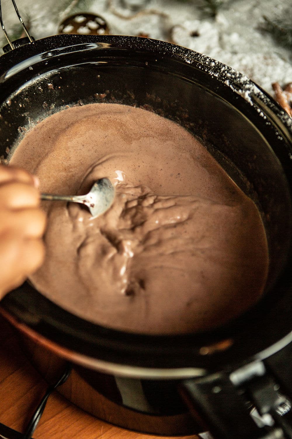 hot chocolate in the slow cooker with a spoon.