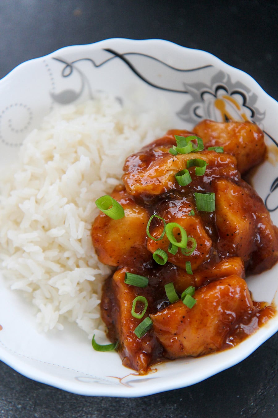 crockpot orange chicken with scallions on top and a side of white rice. 