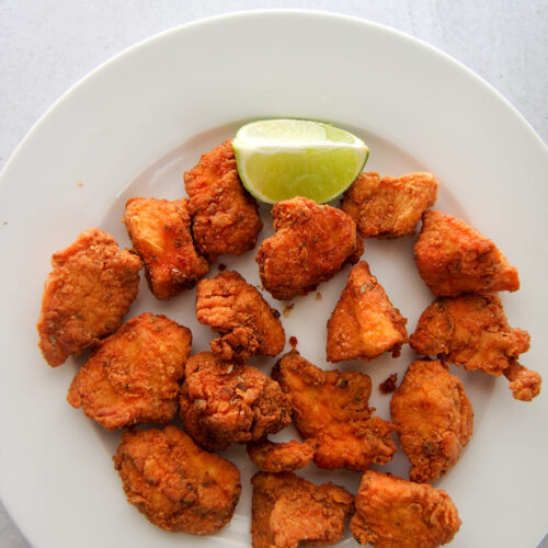 chicharron de pollo aka chicken bites on a white plate with a lime wedge.