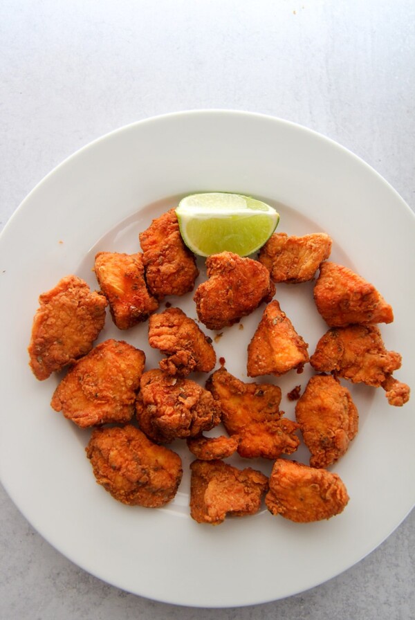 chicharron de pollo aka chicken bites on a white plate with a lime wedge.