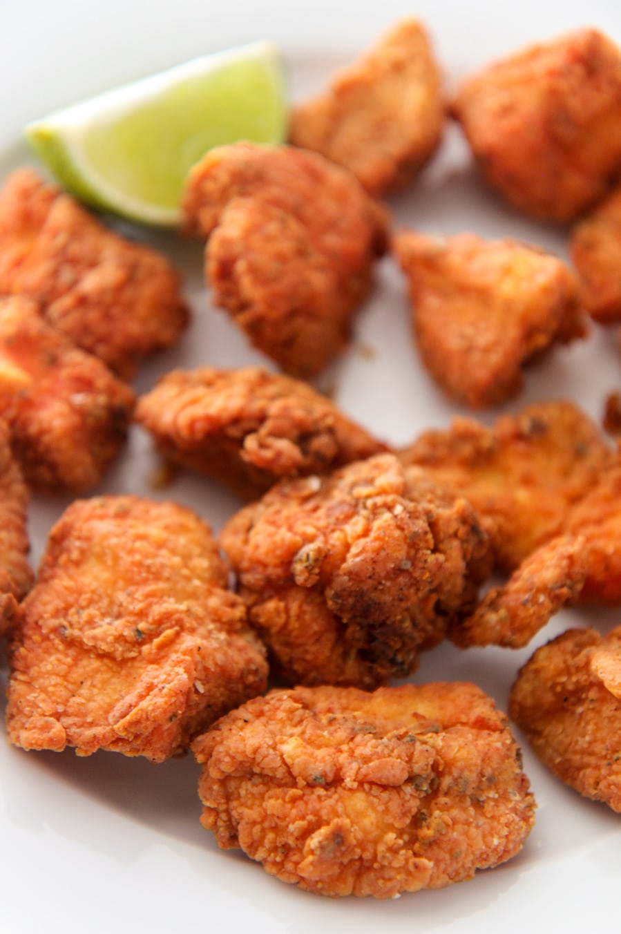 crispy fried chicken bites with a lime wedge up close. 