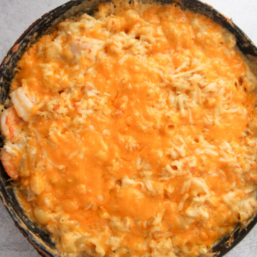 seafood macaroni and cheese in a black cast iron skillet.