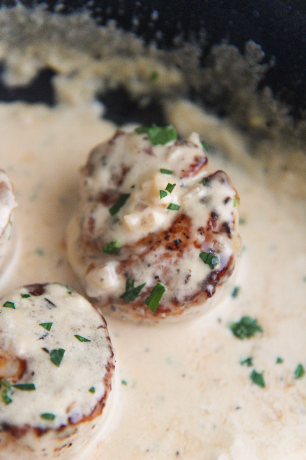 2 scallops tossed in cream sauce and garnished with fresh parsley.