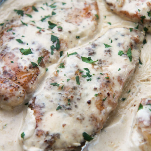 two creamy garlic parmesan chicken breasts with parsley on top.