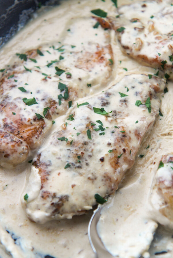 two creamy garlic parmesan chicken breasts with parsley on top.