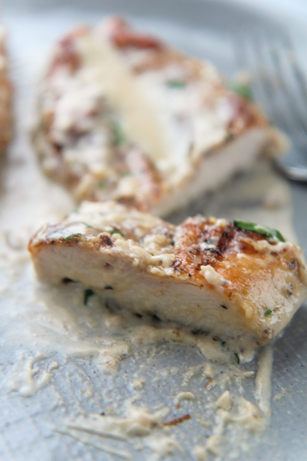 a sliced piece of parmesan chicken on a gray plate. 