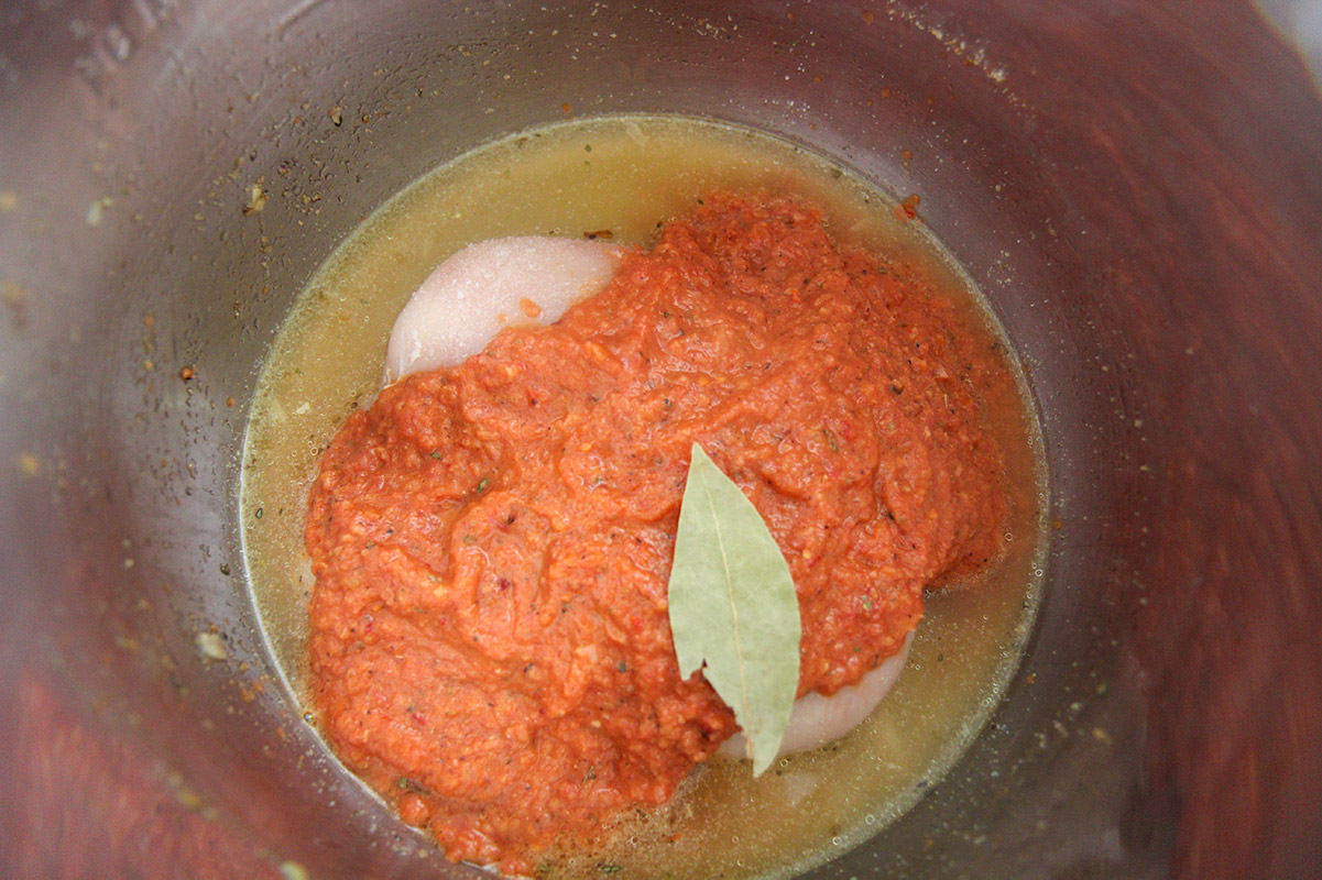 chicken stock, raw chicken breasts, tomato and chipotle sauce, and a bay leaf in the instant pot.