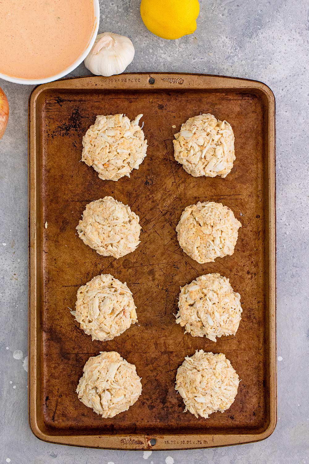 eight crab patties on a baking sheet.