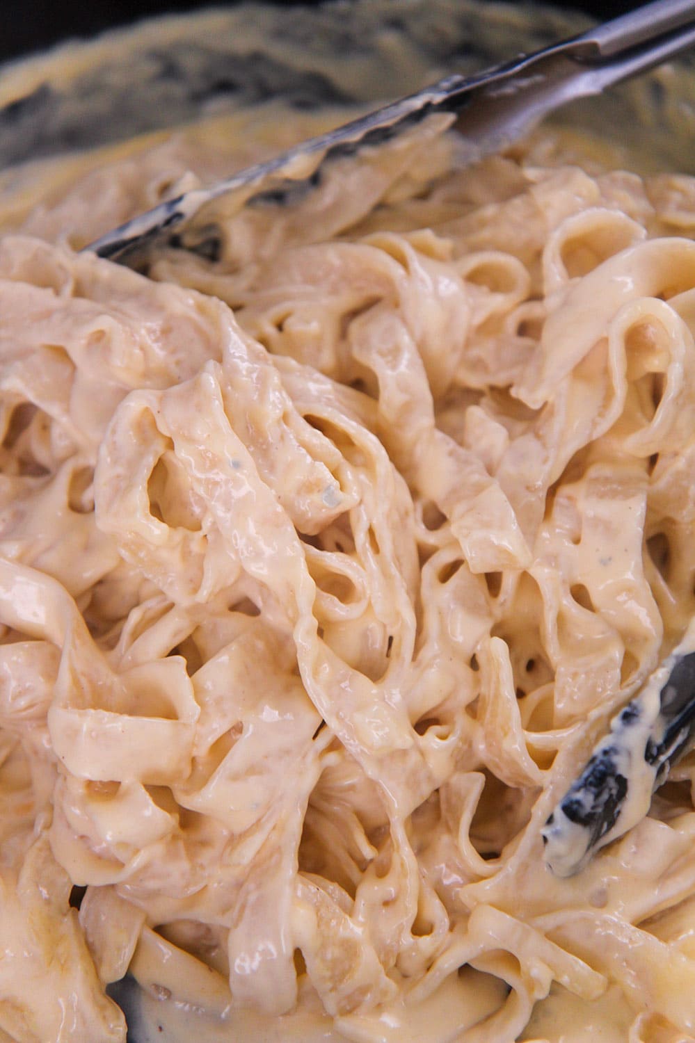 four cheese pasta in a skillet with tongs up close.