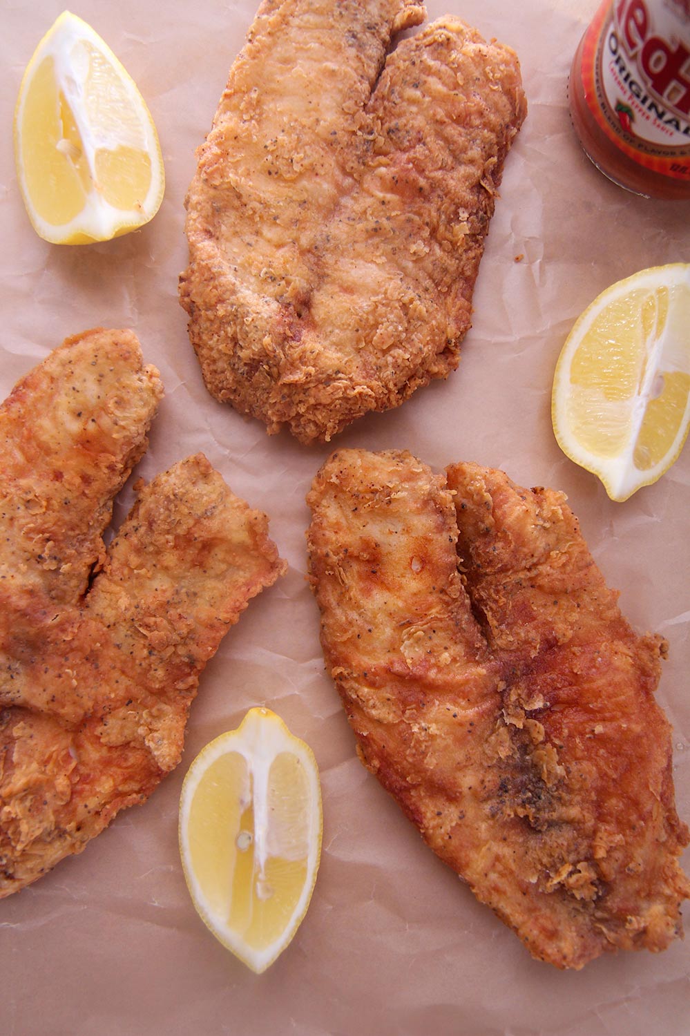 three fried tilapias on brown parchment paper. 