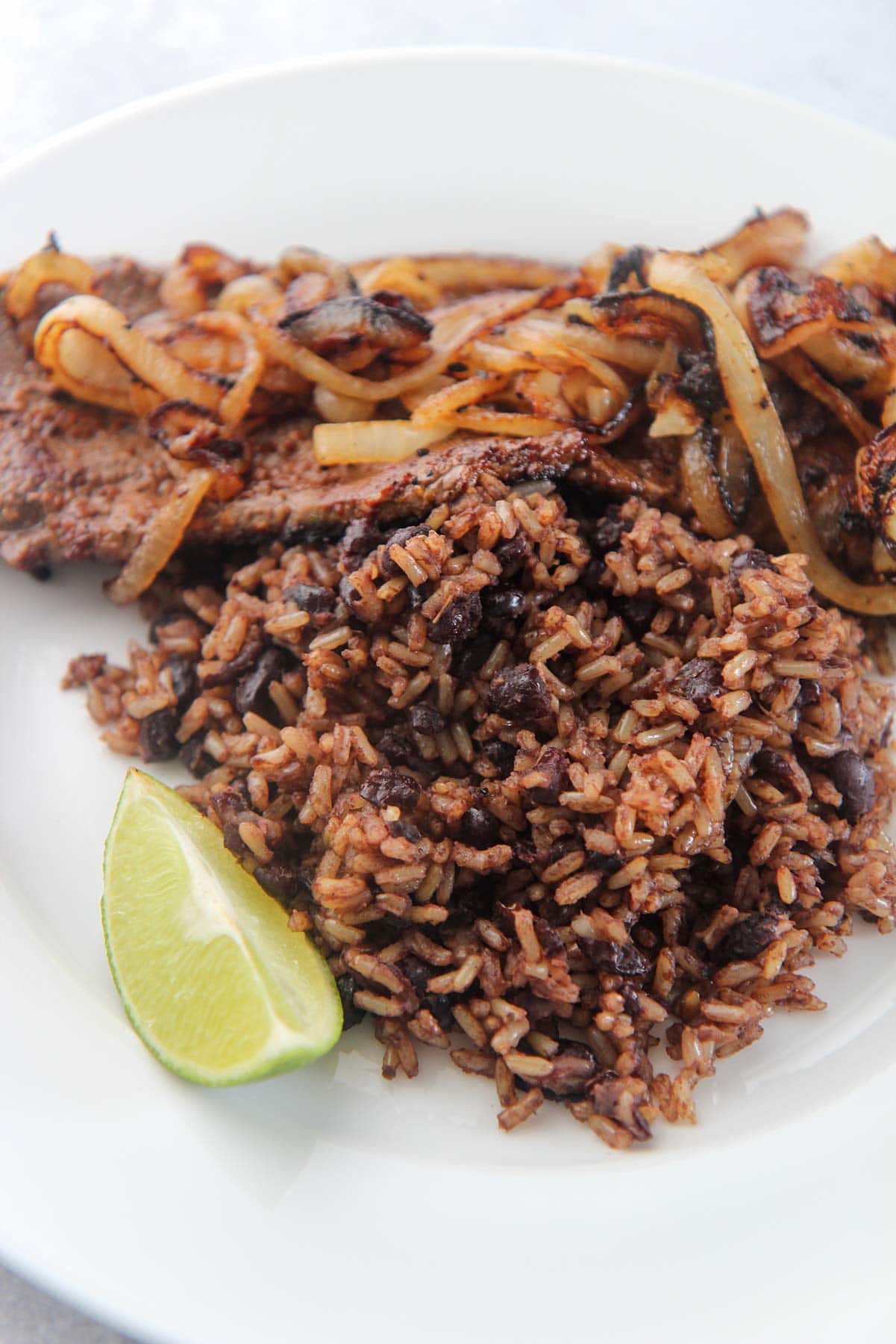 congri with steak, onions, and a lime wedge.