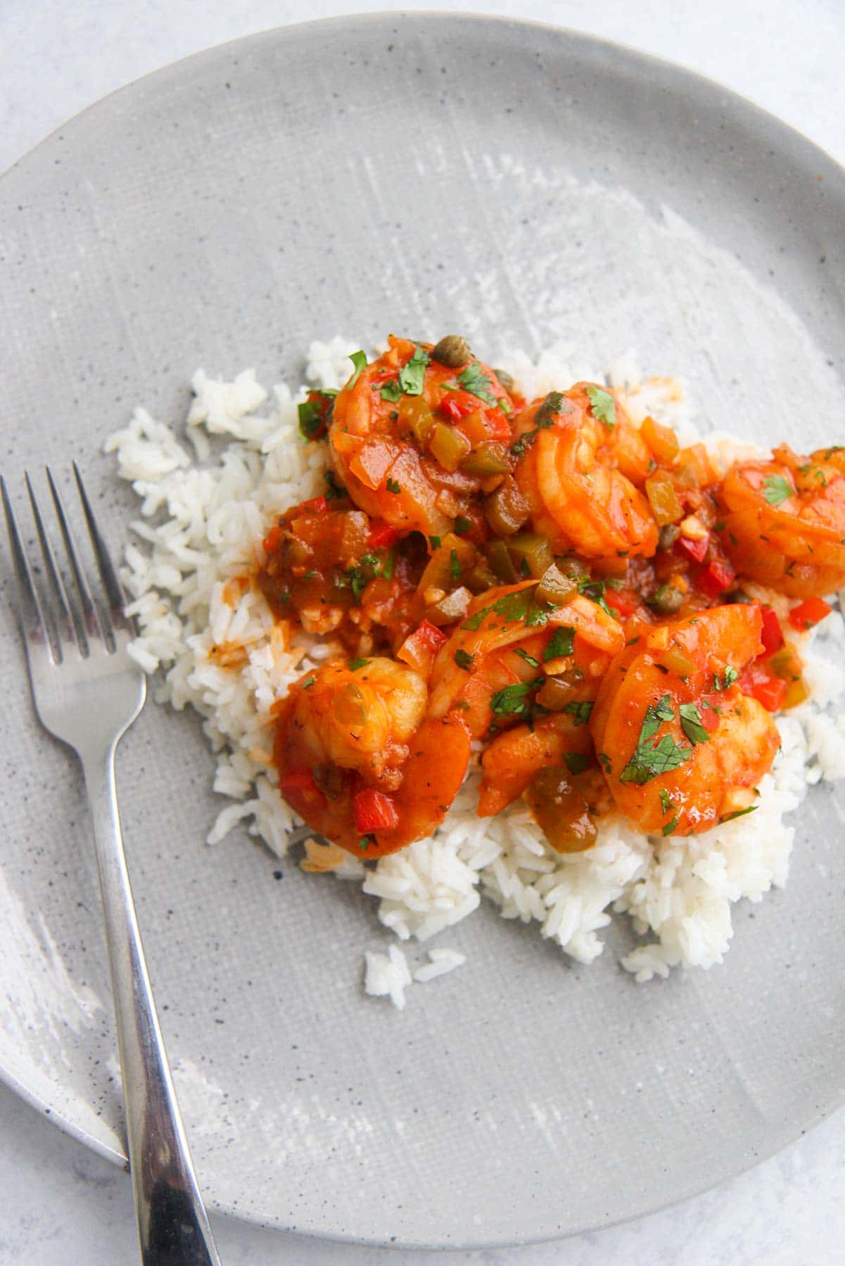 Cuban shrimp over white rice on a plate with a fork. 