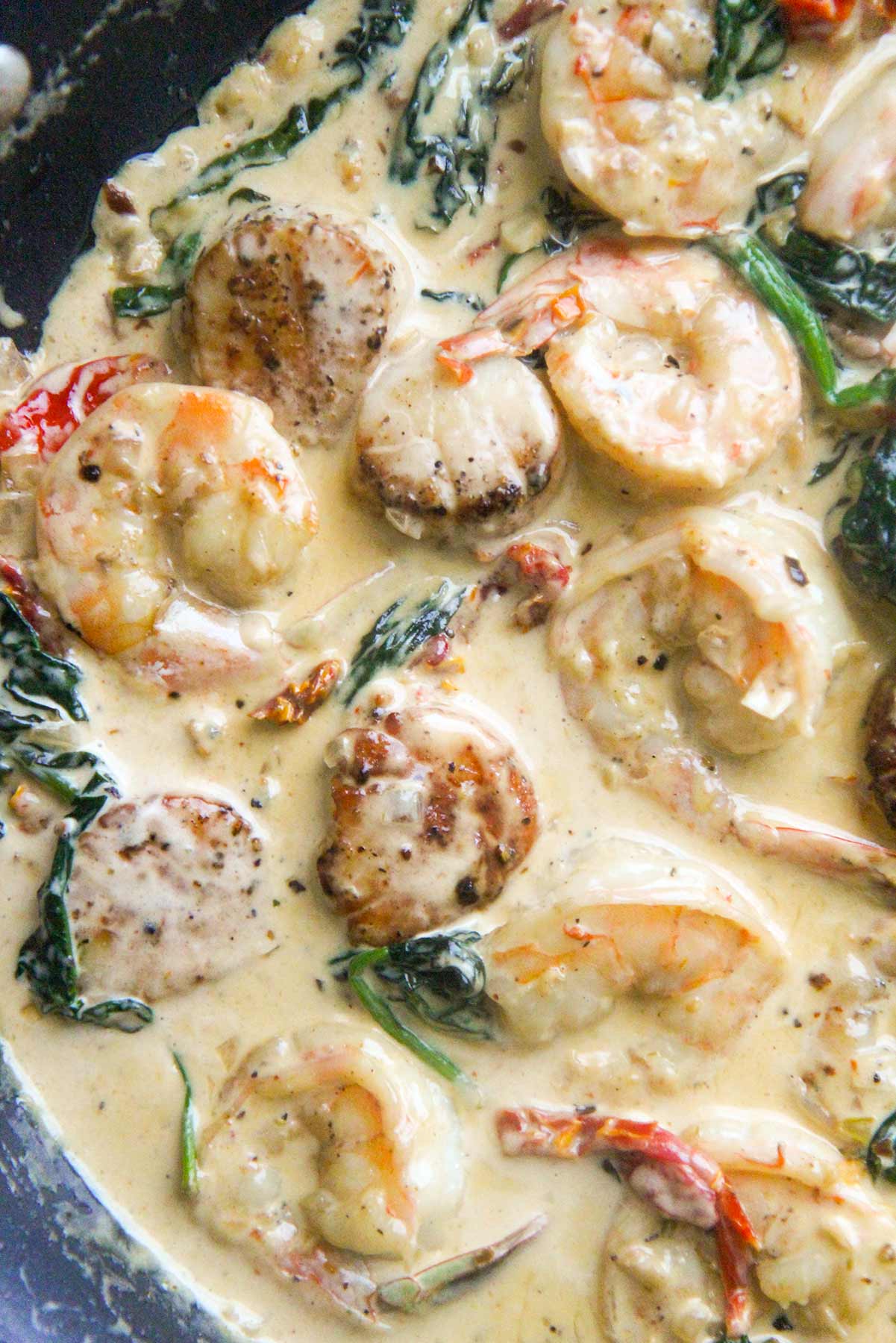Tuscan shrimp and scallops in a skillet up close. 