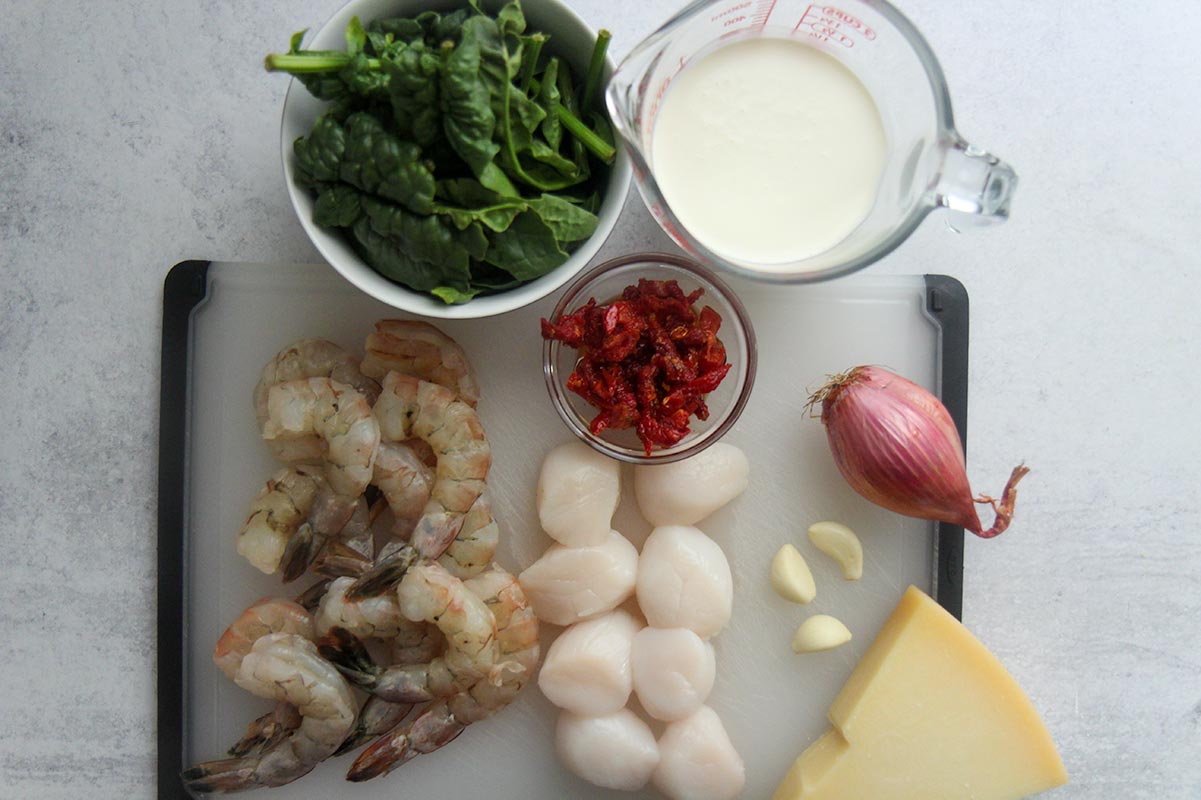ingredients for Tuscan shrimp and scallops. Heavy cream, spinach, shrimp, scallops, sun dried tomatoes, cheese, garlic, and shallots. 