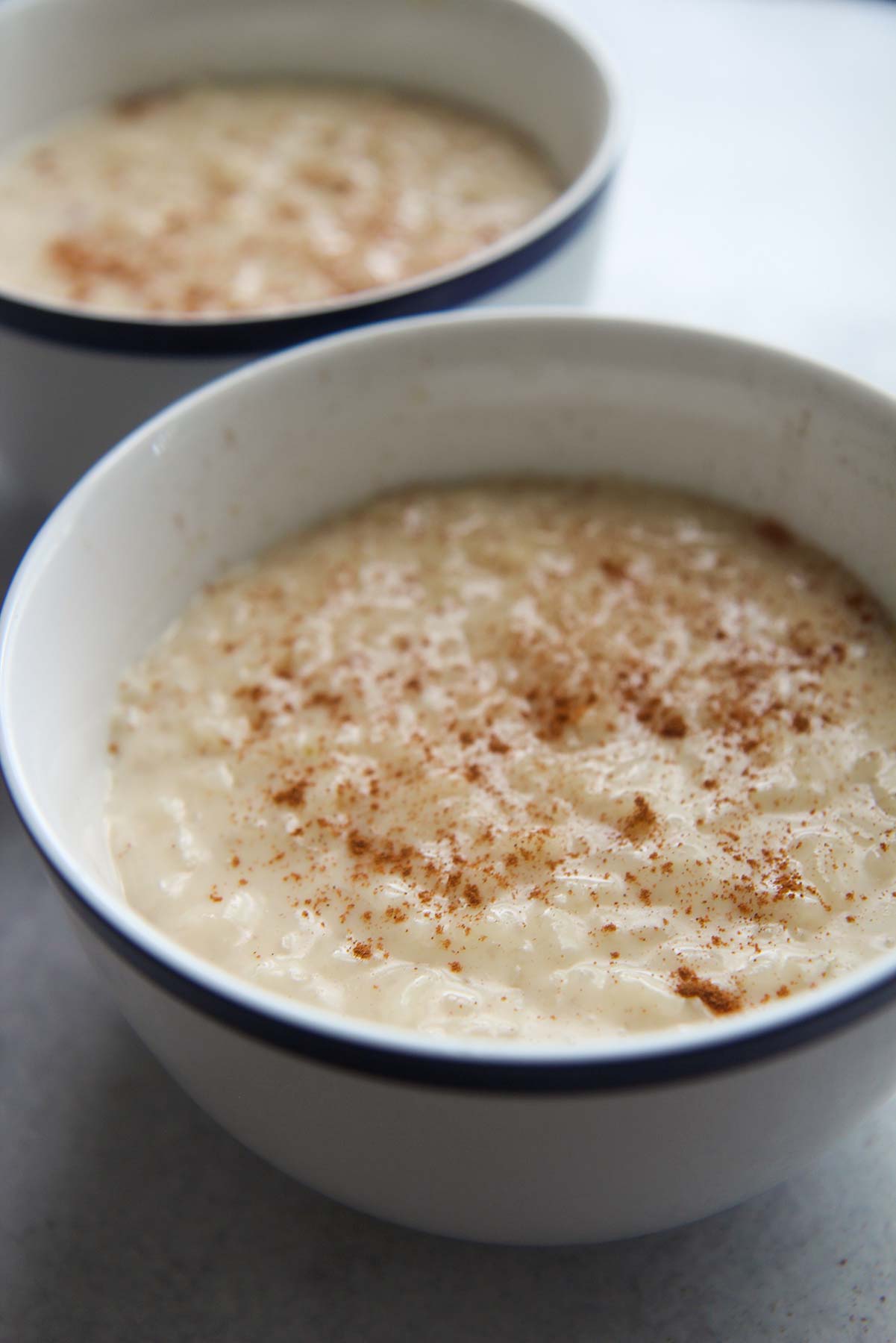 two small bowls filled with rice pudding and ground cinnamon on top. 