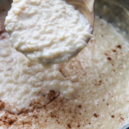 arroz con leche (rice pudding) in a large pot with a wooden spoon.