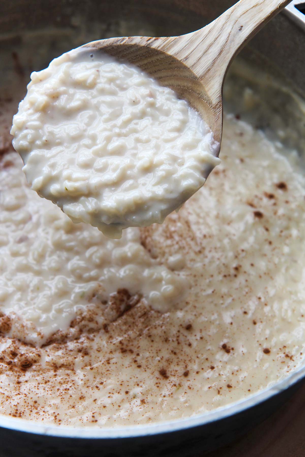 arroz con leche (rice pudding) in a large pot with a wooden spoon.