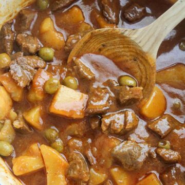 carne guisada de res in a large pot with a wooden spoon.